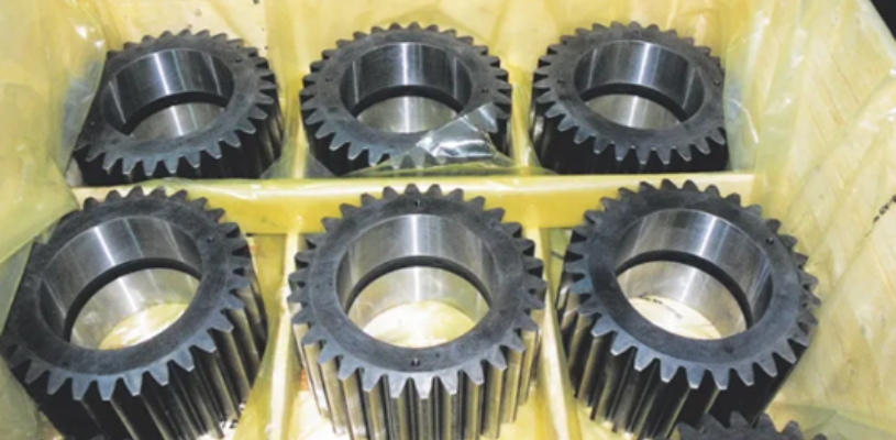 Metal gears sitting inside a box fitted with yellow multimetal VCI film